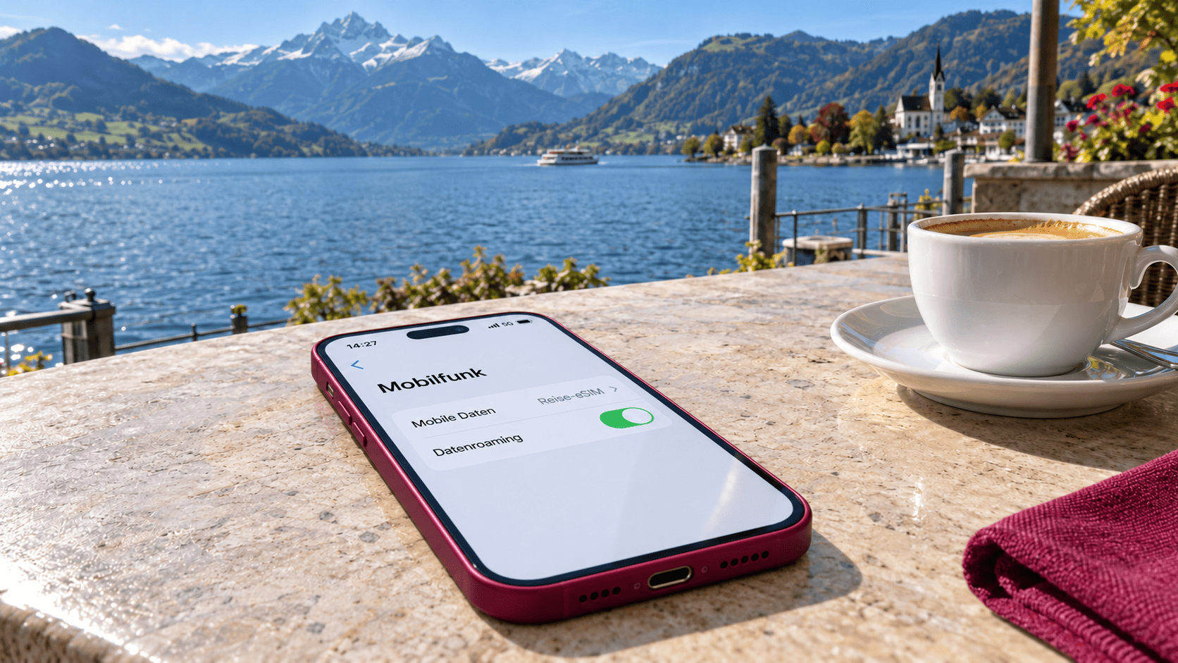 Smartphone mit Reise-eSIM-Einstellungen auf einem Cafétisch mit Blick auf einen See und die Schweizer Alpen.